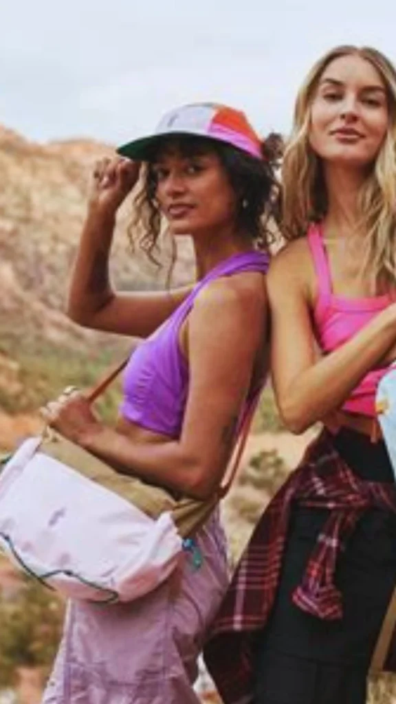 Pinterest pin titled "Test Drive Your Capsule for One Week.webp". The image shows two active women in stylish, colorful workout attire and casual accessories, set against an outdoor landscape. This pin invites women to "test drive" their curated collection to see if it truly works for their daily life, offering a practical approach to refining their Capsule Wardrobe. It highlights how a functional, intentional approach to women's fashion can support an active, versatile lifestyle.