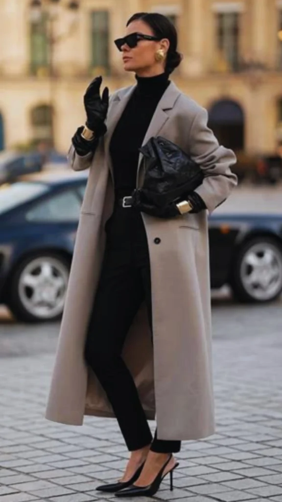 Women's fashion Pinterest pin titled "Why Every Woman Should Consider a Capsule Wardrobe.webp". The image captures a stylish woman walking outdoors in a sophisticated, minimalist ensemble, featuring a neutral long coat, black turtleneck, trousers, and sleek heels. This look exemplifies the elegance and versatility that defines a Capsule Wardrobe, demonstrating how curated, high-quality basics can create an effortlessly polished appearance for any modern woman.