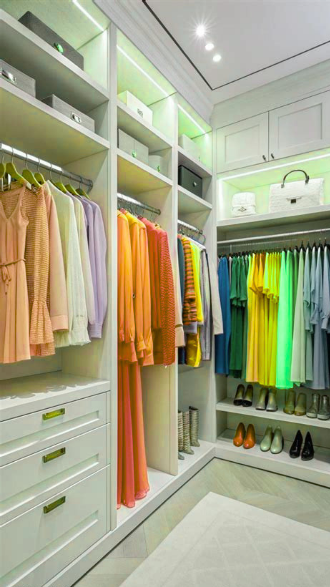 Bright walk-in closet organizational pin via lessloom.com titled "Design Your Wardrobe Around Your Real Workday" for a women's fashion Capsule Wardrobe. Features customized white built-in shelving neatly displaying color-coordinated dresses, blouses, folded knits, boots, and heels. Ideal visual guide for organizing quiet luxury workwear, Scandinavian minimalist closet design, home wardrobe optimization, and building a structured daily clothing layout.